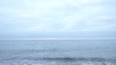 Çakıl plajı gün batımında. Dalgalar sıçramak ve damlacıklar kesin. 4k, ağır çekim