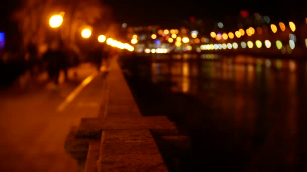 People stroll along the embankment strewn with evening lights. blur. 4K bokeh — Stock Video