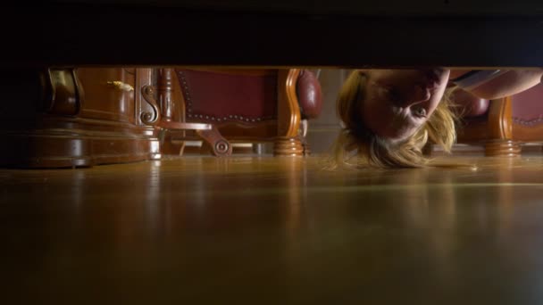 4K, câmara lenta, vista de baixo da cama. Uma mulher com uma lanterna está à procura de algo debaixo da cama . — Vídeo de Stock