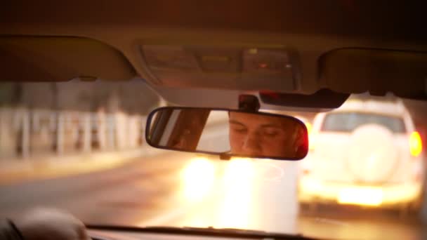 Reflection of the driver of the man in the rearview mirror. a man drives a car around the evening city. 4k, background blur. — Stock Video