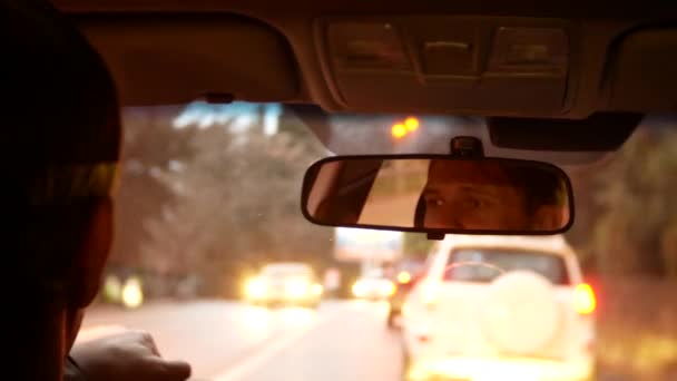 Reflection of the driver of the man in the rearview mirror. a man drives a car around the evening city. 4k, background blur. — Stock Video