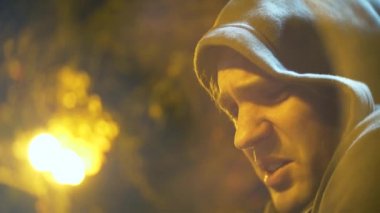 Profil sahibi bir kukuleta ile üzgün bir adam. yakın çekim, arka plan bulanıklık, bokeh. 4k