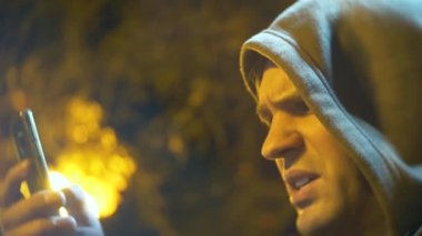 Kukuletalı adam profili cep telefonu arıyorum. yakın çekim, arka plan bulanıklık, bokeh. 4k