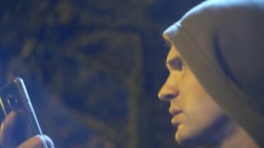 Kukuletalı adam profili cep telefonu arıyorum. yakın çekim, arka plan bulanıklık, bokeh. 4k