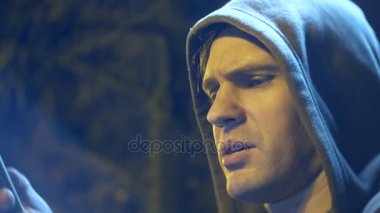 Kukuletalı adam profili cep telefonu arıyorum. yakın çekim, arka plan bulanıklık, bokeh. 4k