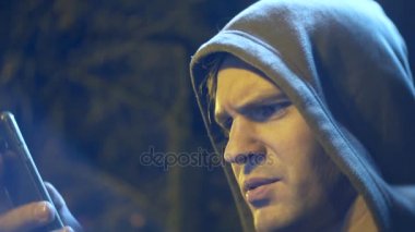 Kukuletalı adam profili cep telefonu arıyorum. yakın çekim, arka plan bulanıklık, bokeh. 4k