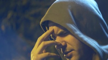 Profil sahibi bir kukuleta ile üzgün bir adam. yakın çekim, arka plan bulanıklık, bokeh. 4k