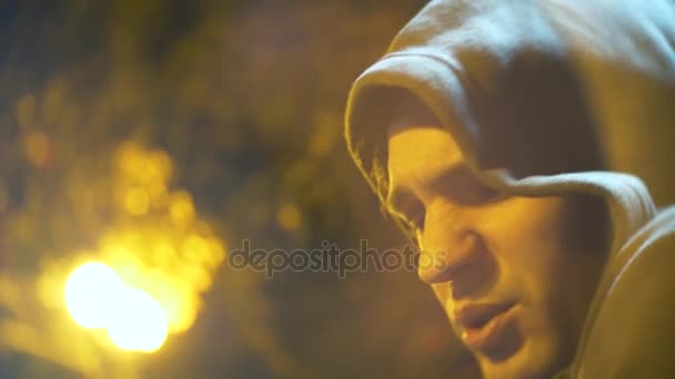 Profile of a sad man with a hood. close-up, background blur, bokeh. 4k — Stock Video