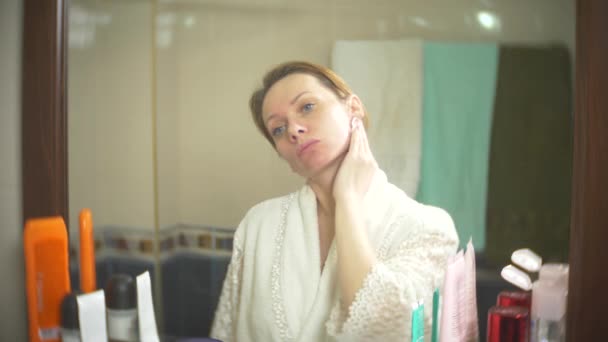 Γυναίκα καθαρισμού προσώπου με μπατονέτα μπροστά από τον καθρέφτη. 4k, αργή κίνηση. γκρο πλαν. θάμπωμα του φόντου. — Αρχείο Βίντεο
