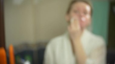 kirli kullanılan pamuk makyaj izleri ile. Ayna önünde, pamuk bez ile yüz temizliğinde kadın. 4k, ağır çekim. yakın çekim. arka plan bulanıklık.