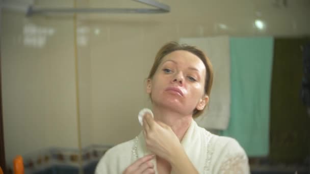 Femme nettoyant visage avec coton-tige devant le miroir. 4k, au ralenti. Gros plan. flou de fond . — Video