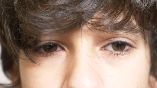 검 고 긴 속눈썹을 가진 소년의 갈색 눈. 그는 긴 곱슬 이에요에서 보인다. 4 k, 슬로우 모션, 클로즈업 — 비디오