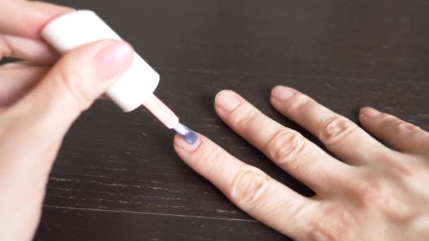 Žena si maluje nehty růžovým lakem na nehty. 4k, close-up, slow-motion — Stock video