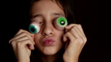 yakın çekim. neşeli bir genç kızın gözleri, gözleri için benzer büyük bir yuvarlak şeker getiriyor. 4k.