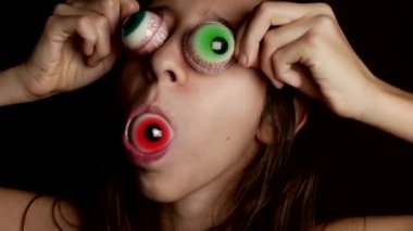 yakın çekim. neşeli bir genç kızın gözleri, gözleri için benzer büyük bir yuvarlak şeker getiriyor. 4k.