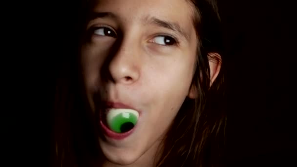 Close-up. a cheerful teenage girl takes in the mouth large round candy, similar to the eyes. 4k. — Stock Video