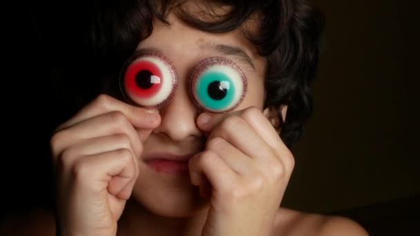 Nahaufnahme. Ein fröhlicher Teenager bringt dem Auge große runde Bonbons, ähnlich den Augen. 4k. — Stockvideo