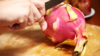 egzotik meyveler masanın üzerinde. 4k, parçalar halinde kesilmesi bir kesme tahtası üzerinde bir bıçakla bir dragonfruit eller
