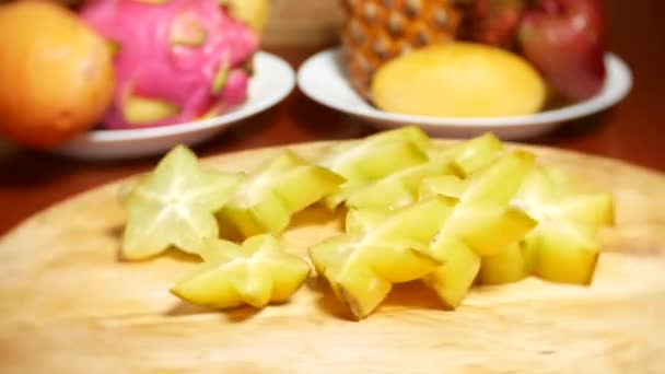 Frutti esotici sul tavolo. 4k, Una carambola tagliata a pezzi ruota su un tagliere . — Video Stock