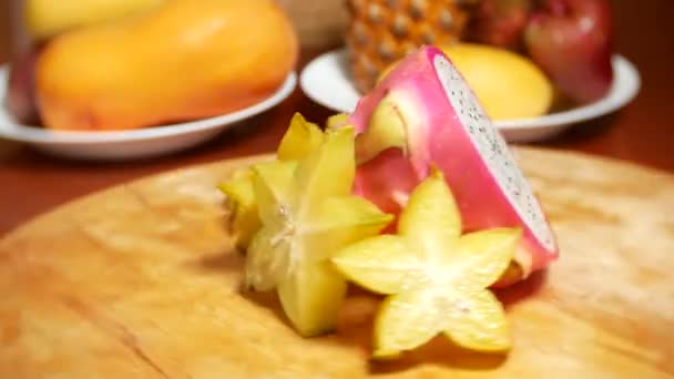 Exotic fruits on the table. 4k, carambola and Dragonfruit, cut into pieces, rotates on a cutting board. — Stock Video