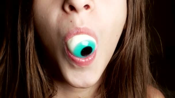 Close-up. a cheerful teenage girl holds large round candies in her mouth, similar to the eyes. 4k. — Stock Video