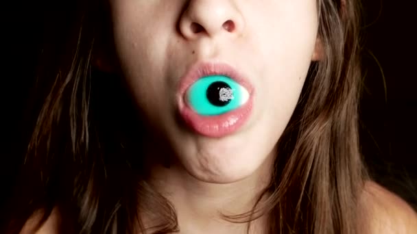 クローズ アップ。陽気な十代の少女は、彼女の口、目のように大きな丸いお菓子を保持しています。4 k. — ストック動画