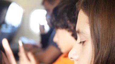 Yolcular uçağın uçuş sırasında Gadget'ları kullanın. Bir tablet telefon uçak kullanan genç kız. Çocuk uçak, 4k