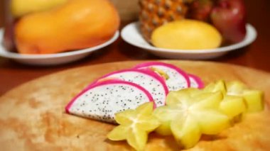 egzotik meyveler masanın üzerinde. 4k, carambola ve Dragonfruit, parçalar halinde kesilmiş bir kesme tahtası üzerinde döner.