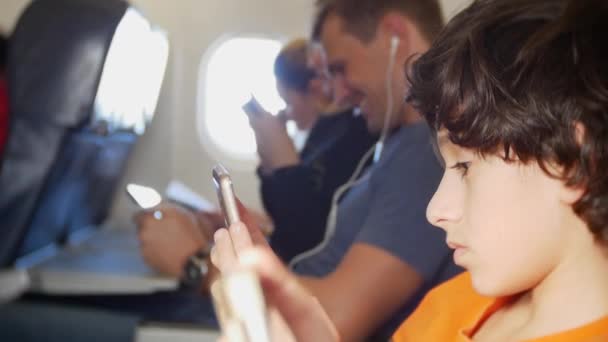 Pasażerowie samolotu za pomocą gadżetów podczas lotu. Młoda dziewczyna przy użyciu telefonu tabletki w samolocie. Dziecko w samolocie, 4k — Wideo stockowe