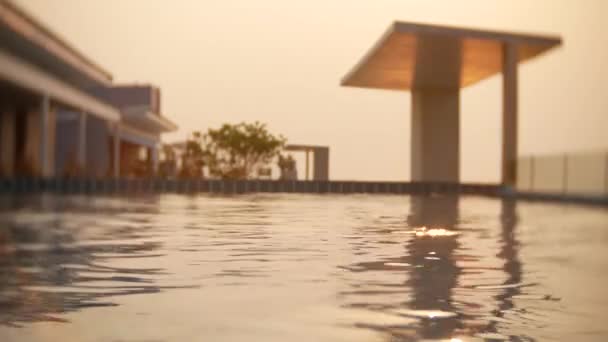 Una lujosa piscina en el techo de la casa con vistas al mar. En la puesta del sol. 4k, cámara lenta, deslumbramiento solar en el agua. desenfoque de fondo — Vídeos de Stock