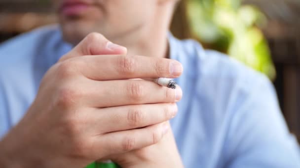 Un joven bebiendo cerveza y fumando cigarrillos al aire libre. 4k, desenfoque de fondo — Vídeo de stock