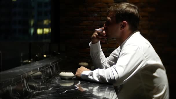Молодой человек курит сигарету в баре. 4k — стоковое видео