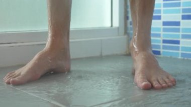 4k, ağır çekim. Duşta erkek bacak yakın çekim. genç adam bir duş alır.
