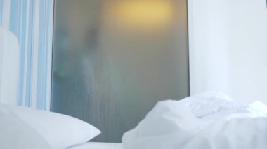 4k, ağır çekim. Tanınmayan kız duş alır. biri yatak odası ve banyo arasında şeffaf duvarı baktığı. Bulanık cam arkasındaki kadın. Kadın banyoda.