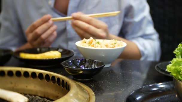 Lunch på en kinesisk restaurang. En man äter ris med grönsaker pinnar. 4k, närbild — Stockvideo