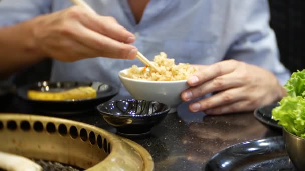 Oběd v čínské restauraci. Muž jí rýže se zeleninou hůlky. 4k, detail — Stock video