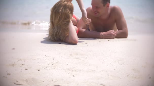 Ein Liebespaar liegt am Strand im Sand und küsst sich, an einem klaren, sonnigen Tag. 4k, Zeitlupe — Stockvideo