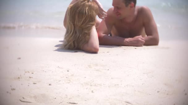 A couple of lovers lie on the sand on the beach and kiss, on a clear sunny day. 4k, slow motion — Stock Video