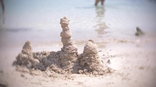 Zandkasteel op het strand, een onherkenbaar familie maakt een zandkasteel op een openbaar strand. 4k, blur, slow-motion — Stockvideo