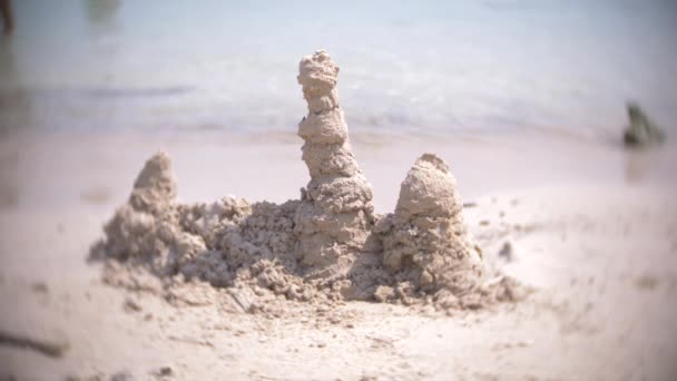 Castello di sabbia sulla spiaggia, una famiglia irriconoscibile rende un castello di sabbia su una spiaggia pubblica. 4k, sfocatura, rallentatore — Video Stock