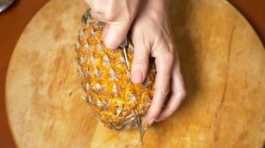 egzotik meyveler masanın üzerinde. 4k, üstten görünüm, ağır çekim. Eller bir ananas kesme tahtası üzerinde bir bıçak ile kesmek.