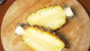 egzotik meyveler masanın üzerinde. 4k, üstten görünüm, ağır çekim. Parçalar halinde dilimlenmiş ananas kesme tahtası üzerinde döner.