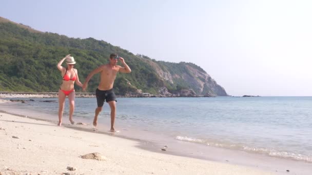 Ein Paar läuft am Strand entlang, Händchen haltend, ein Mann und eine Frau. Touristen am Meer ruhen sich aus. Zeitlupe, 4k — Stockvideo