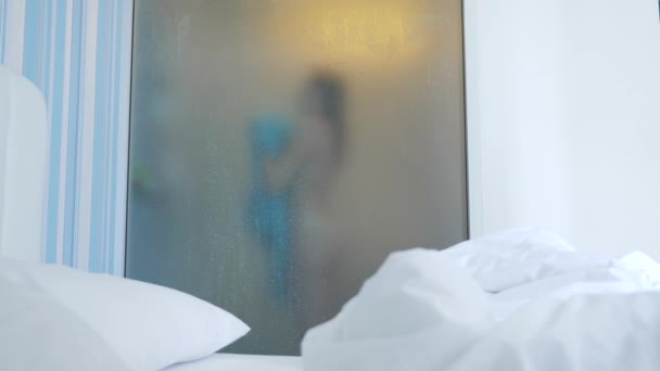 4k, au ralenti. fille méconnaissable, s'est essuyé avec une serviette. quelqu'un regarde shes à travers le mur transparent entre la chambre et la salle de bain. La femme derrière le verre flou . — Video