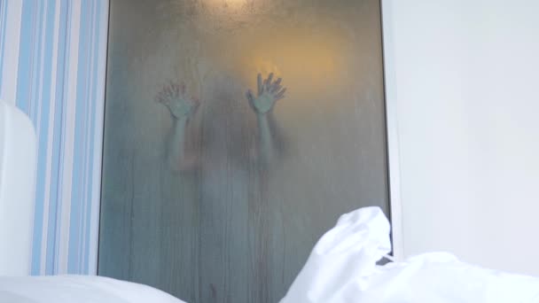 4k, slowmotion. okänt par man och kvinna omfamna och kyssa i duschen. Visa genom ett dimmigt glas, en genomskinlig vägg mellan sovrummet och badrummet — Stockvideo