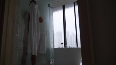 Banyoda genç adam. yakışıklı bir adam bir havlu duştan sonra silinmiş. 4k, ağır çekim