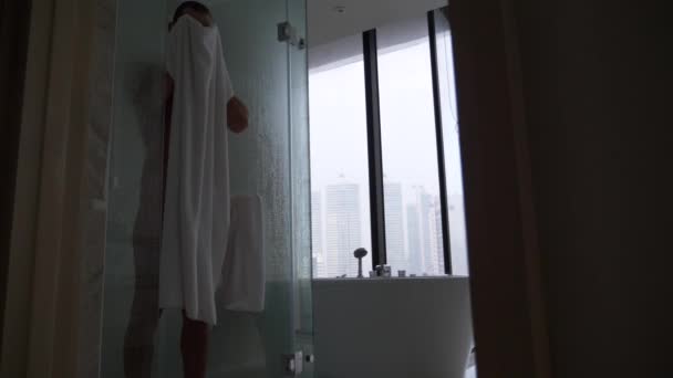 Jovem na casa de banho. Um tipo bonito é limpo por uma toalha depois de um duche. 4k, câmera lenta — Vídeo de Stock