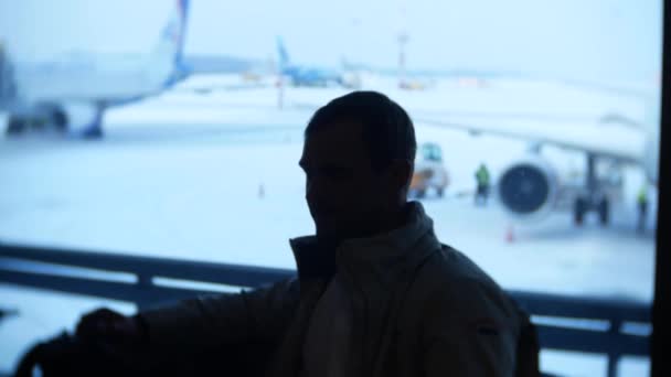 Неизвестный мужчина ждет в аэропорту перед окном. 4k — стоковое видео