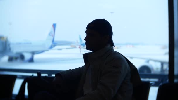 Невідомий чоловік чекає в аеропорту перед вікном. 4k — стокове відео