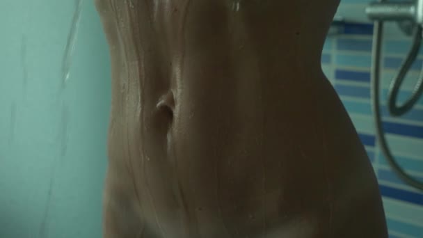 Gros plan, un corps mince de femmes sous les ruisseaux d'eau. la fille prend une douche. 4k, au ralenti . — Video